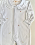 White baby romper with ruffled collar and embroidered details on a light background
