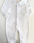 White baby onesie with ruffled collar on a light gray background